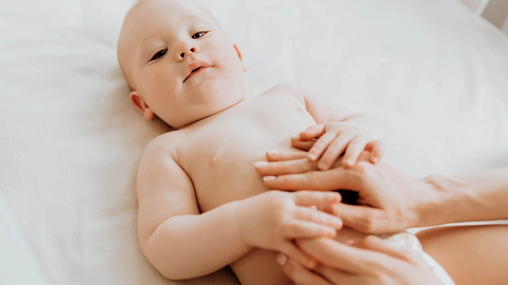 Calm baby lying down during gentle tummy massage